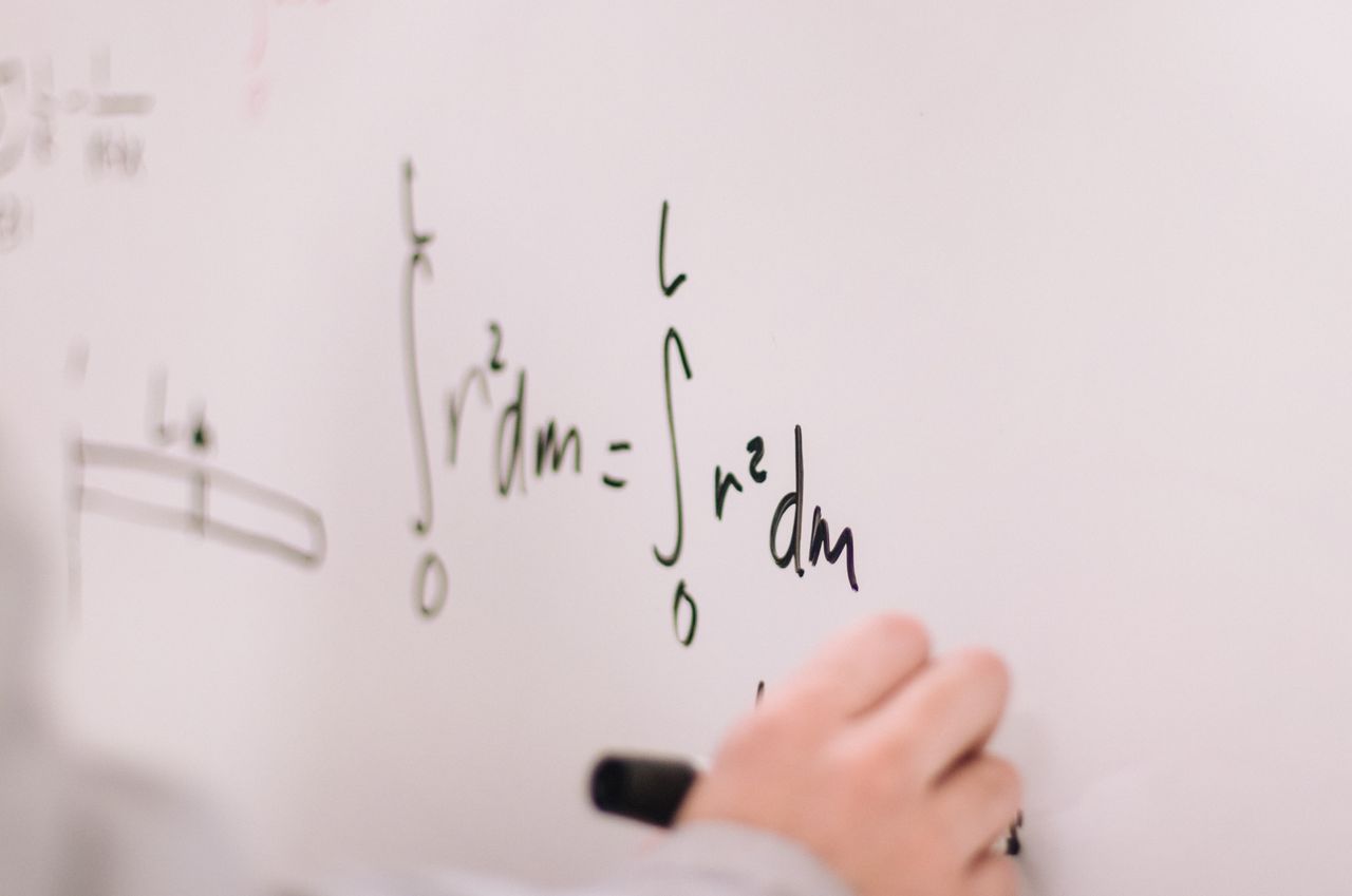 services-03 Person writing math equations on a whiteboard, focusing on integrals and formulas.